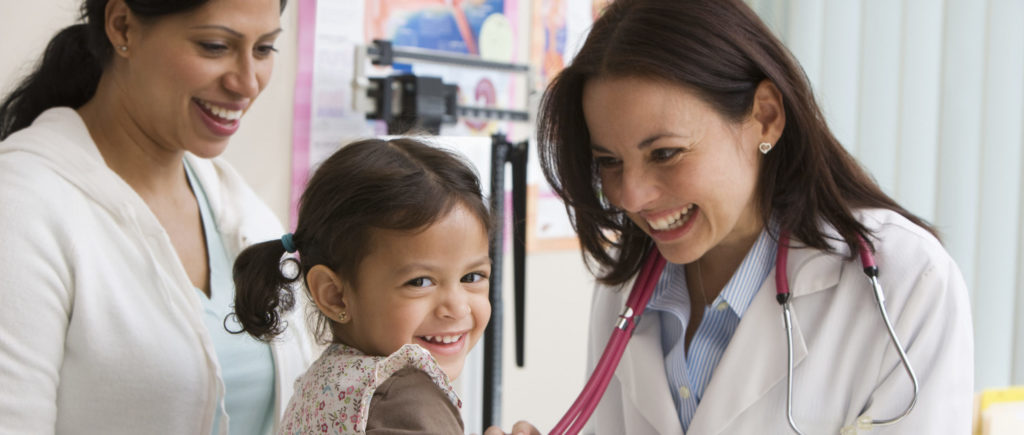 Toddler girl laughing while doctor examines